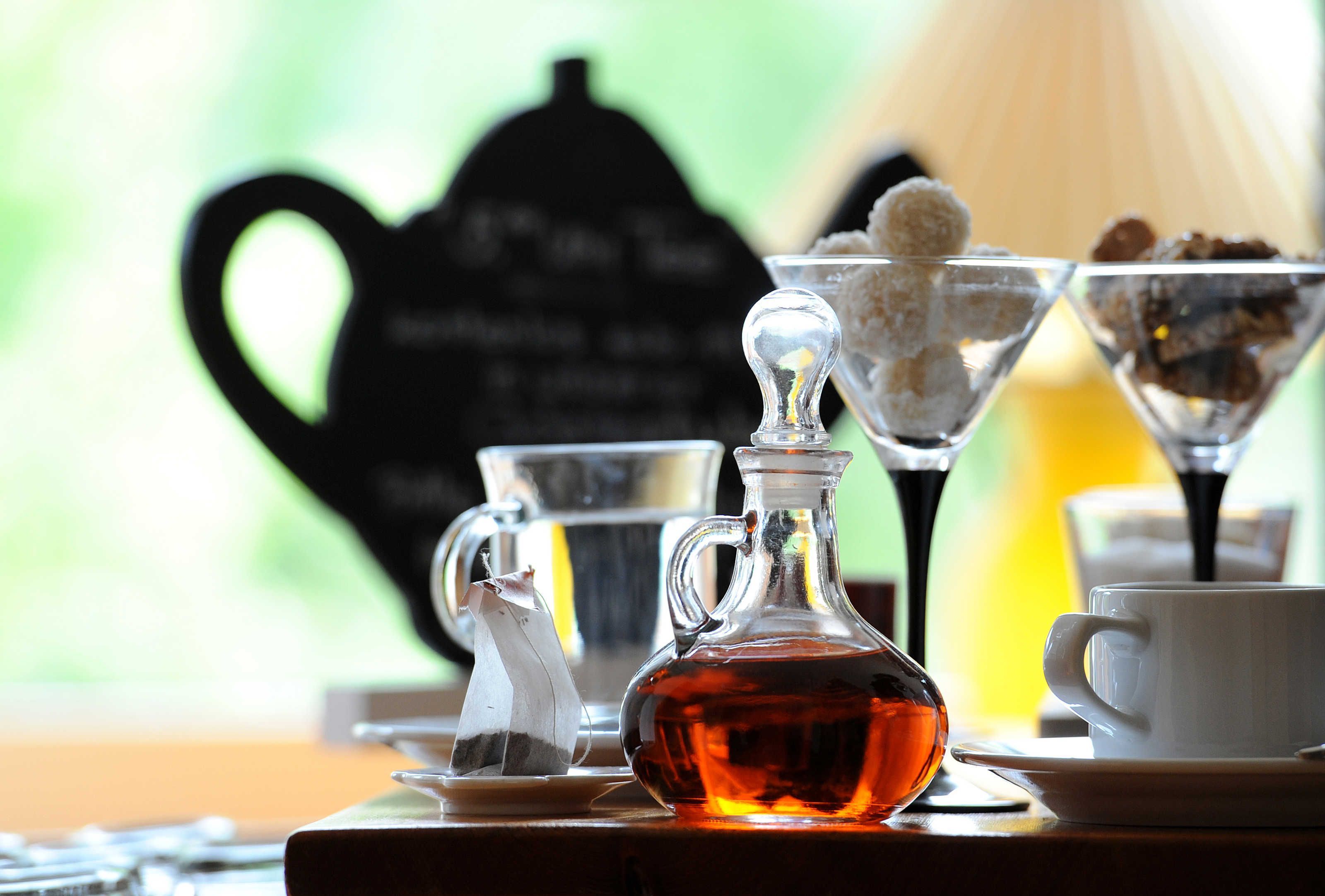 Una mesa con una tetera, una jarrón de vidrio, una taza y un azucarero.