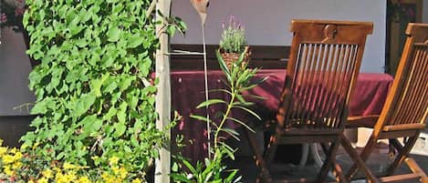 Una silla de madera, una decoración con forma de corazón y una jardinera de madera con plantas.