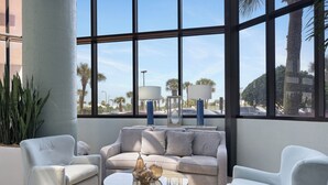 A modern living room with a sofa, two armchairs, a coffee table, and a view through large windows. - Phoenix VI 1101 by Liquid Life (Orange Beach)
