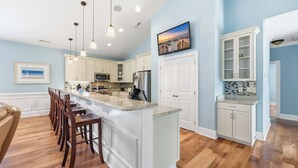 A kitchen with a central island, white cabinetry, and a large window.