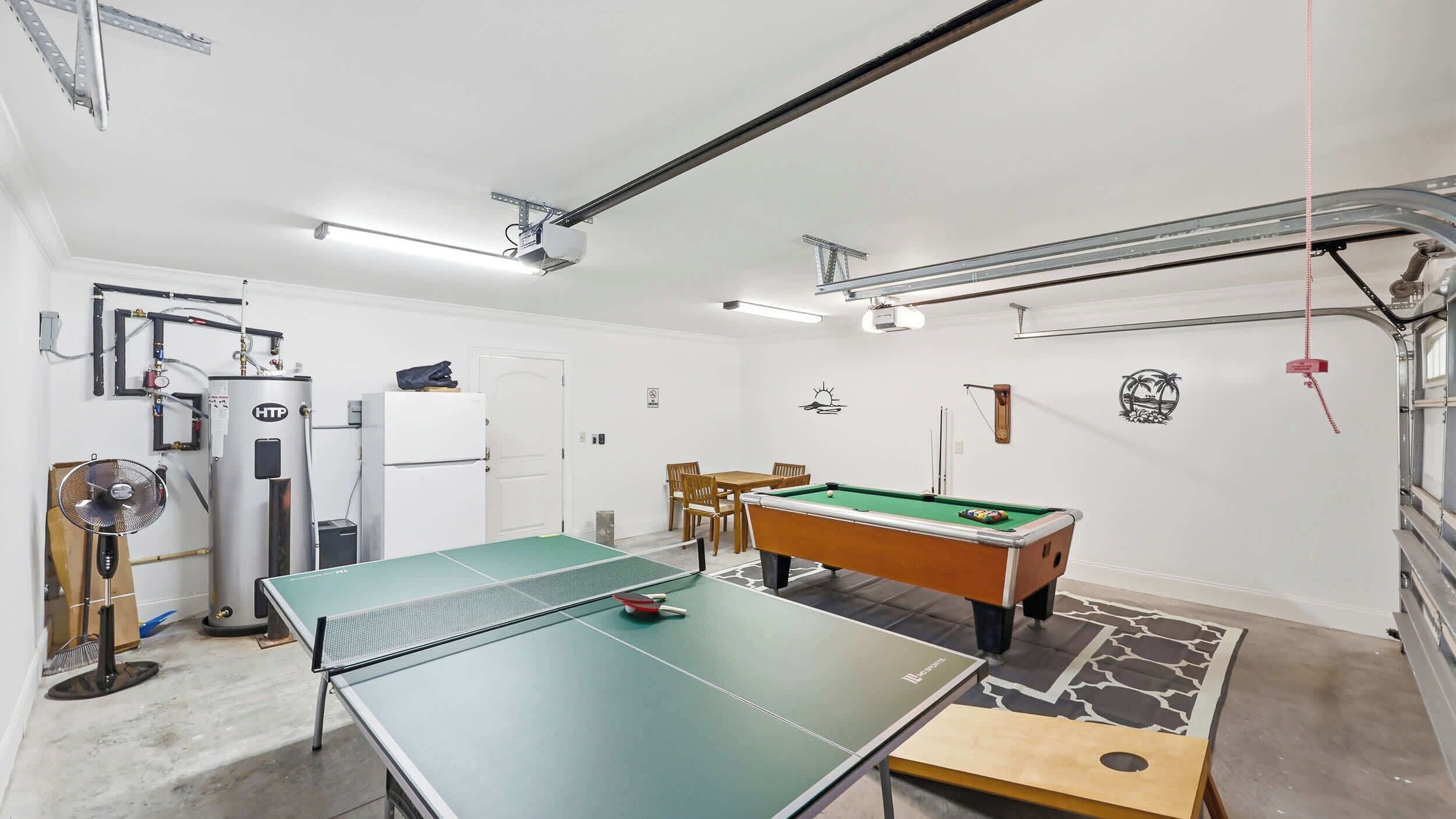 Una habitación con mesa de ping pong, mesa de billar, ventilador, calefactor y una puerta.