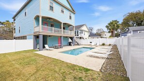 A two-story house with a pool, a covered patio, and a fenced backyard.