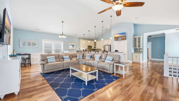 A spacious living room with a sectional sofa, a coffee table, and a ceiling fan.