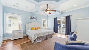 A bedroom with a bed, nightstands, a ceiling fan, and a view through a glass door.