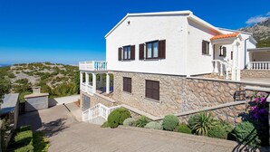 A white building with stone accents, a balcony, and a view of the landscape. - 1 bedroom stunning apartment in Jablanac (Jablanac)