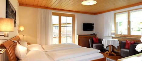 Een kamer met een houten bed, een televisie, een eettafel en een bank.