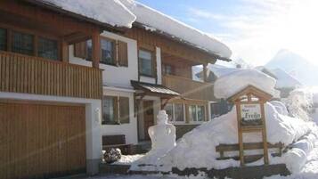 A wooden building with a snow-covered roof, a sign reading 'Hotel Evelin,' and a snowman decoration.