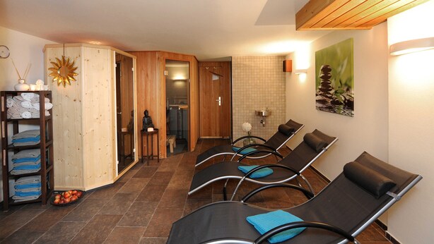 Un cuarto de spa con paneles de madera, un adorno de sol, un perchero y un cuadro colgado en la pared.
