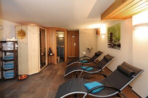 A spa room with wooden paneling, a sun decoration, a towel rack, and a wall-mounted picture. - Room Barbarakraut - WohlfühlHaus Evelin (Au)
