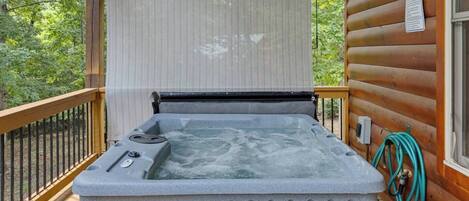A hot tub on a wooden deck with a view of trees.