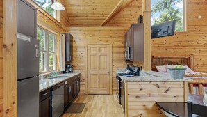 Een kleine keuken met houten wanden, een centrale deur en een eethoek met een tafel en stoelen.