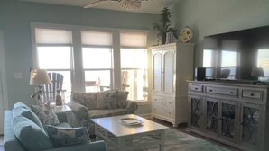 A living room with a sofa, armchair, coffee table, and a cabinet with a television. - Beach Front Condo With Wonderful Ocean View  (Indian Beach)