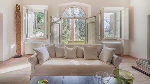 A room with a beige sofa, a wooden sculpture, and a view through open windows. - Awesome home in Lari -PI- (Lari -PI-)