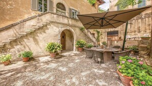 An outdoor patio with a table and chairs, surrounded by potted plants and a stone staircase. - Awesome home in Lari -PI- (Lari -PI-)
