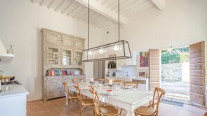 A spacious kitchen with white cabinets, a dining table set for four, and a large window providing natural light. - Awesome home in Lari -PI- (Lari -PI-)