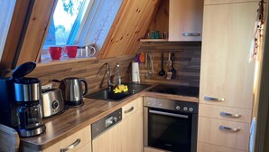 Eine Küche mit Holzausstattung, einem Bosch-Ofen, einer Kaffeemaschine und Küchenutensilien, die an der Wand hängen.