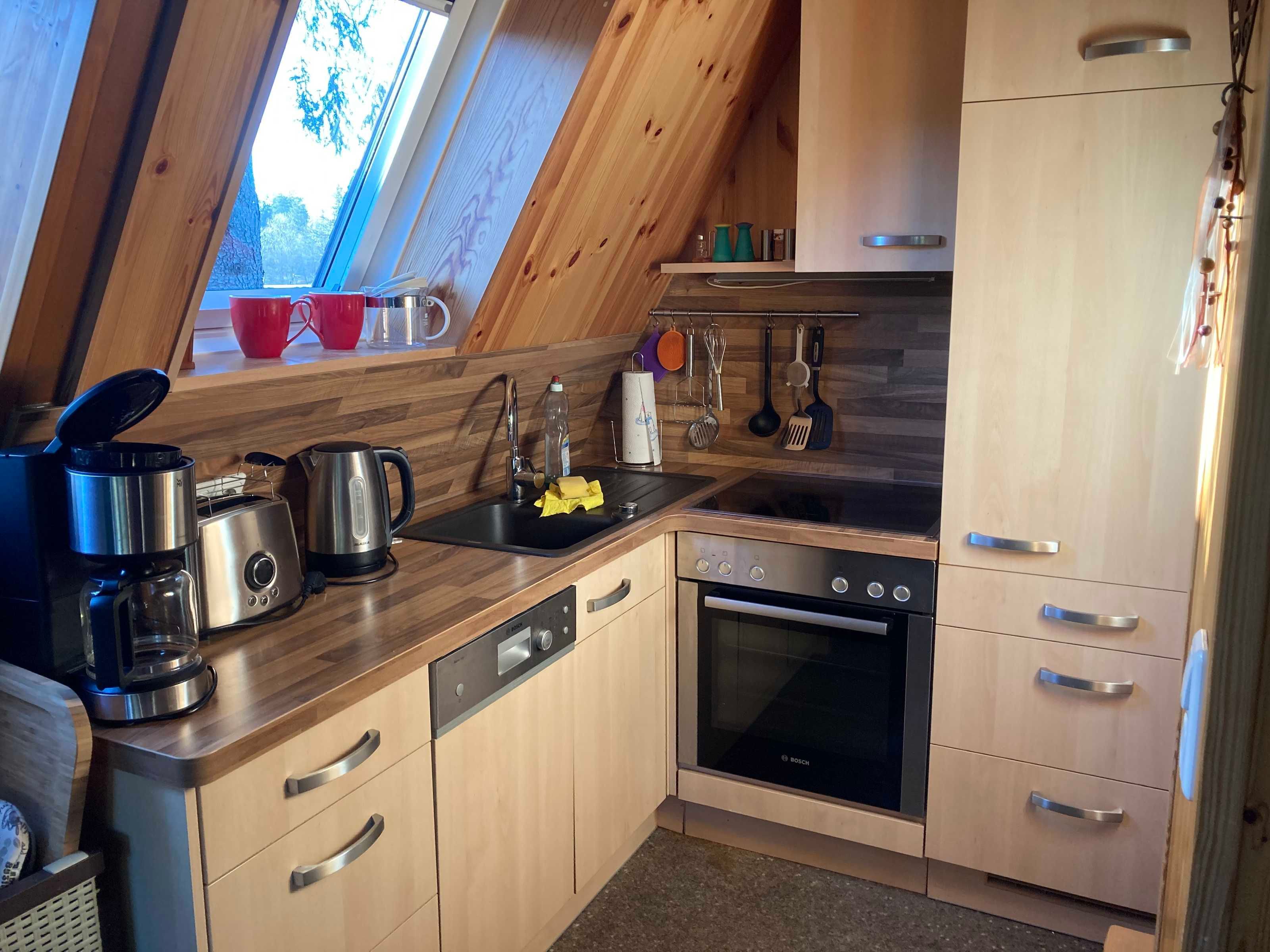 A kitchen with wooden cabinets, a Bosch oven, a coffee maker, and utensils hanging on the wall.