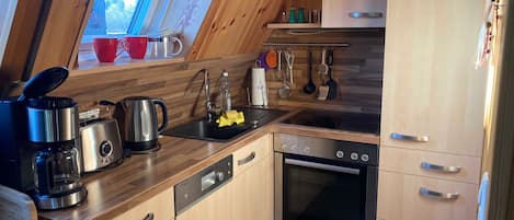 A kitchen with wooden cabinets, a Bosch oven, a coffee maker, and utensils hanging on the wall.