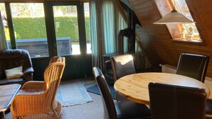 Ein gemütliches Zimmer mit einem runden Holztisch, schwarzen Ledersesseln, einem Korbstuhl und einem braunen Ledersofa.