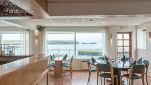 Un espace repas avec vue sur la mer, des meubles en bois et un comptoir de bar.