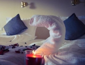 Ein Bett mit weißer Decke und einem blauen Kopfkissen.