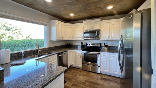 A modern kitchen with white cabinets, stainless steel appliances, granite countertops, and a view of greenery outside. - Sports Village Cliffside Getaway/3 bed/2 bath w/View located in St George, UT (St George)