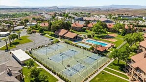 A residential area with a large tennis court, a swimming pool, and houses with red roofs. - Sports Village Cliffside Getaway/3 bed/2 bath w/View located in St George, UT (St George)