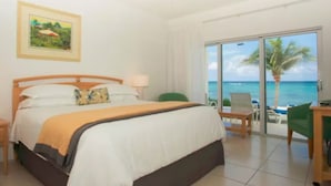 Ein Hotelzimmer mit Bett, Schreibtisch, Sessel und Deckenventilator, mit Blick aufs Meer.