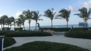 Ein Strandabschnitt mit Palmen, einem Pool und einem Rettungsturm.