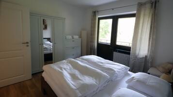 Ein Schlafzimmer mit Bett, Kleiderschrank, Heizkörper und einem fenster mit Vorhängen.