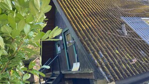 Ein Gebäude mit einem geneigten Dach, einer hölzernen Treppe, die zu einer Tür führt, und einem kleinen Vorbereich.