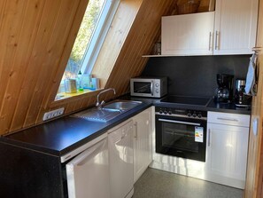 A kitchen with a microwave, stove, sink, and cabinets.