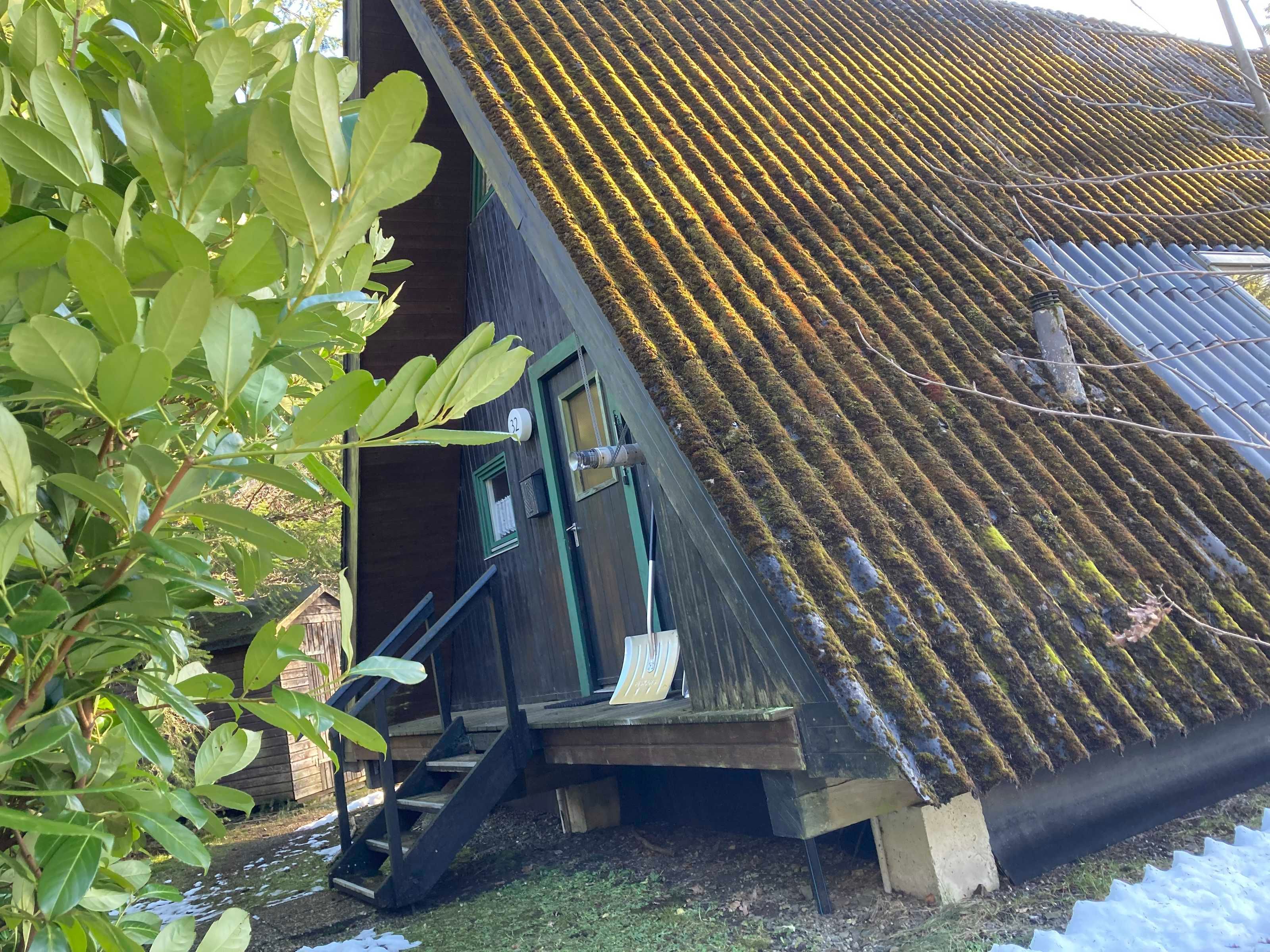 A building with a sloped roof, a wooden staircase leading to a door, and a small porch area.