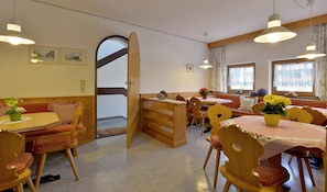 A cozy dining area with wooden furniture, a large open door leading to a balcony, and a window with floral curtains. - Apartment for 6 persons - Apartment house Kaltenbach-Stumm (Stumm)
