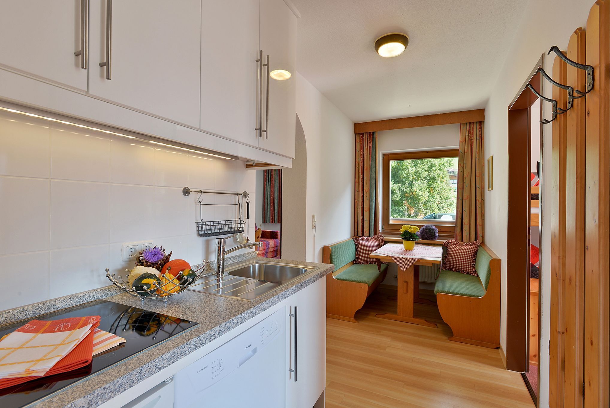 A compact kitchen with a sink, stove, and a dining area with a table and chairs.