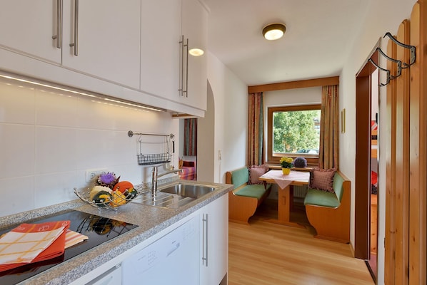 A compact kitchen with a sink, stove, and a dining area with a table and chairs.