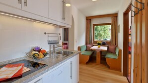 A compact kitchen with a sink, stove, and a dining area with a table and chairs.