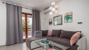 A modern living room with a sectional sofa, a glass coffee table, and a balcony with grey curtains. - Cozy apartment in Cesarica with house sea view (Cesarica)