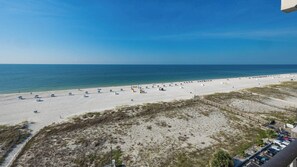 Una spiaggia con cielo sereno, litorale sabbioso e alcuni ombrelloni.