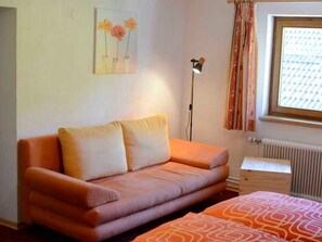 Una habitación con un sofá, una lámpara, un radiador y una ventana con cortinas.