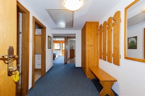 A hallway with wooden doors, a bench, and a coat rack.