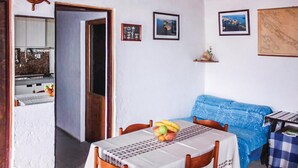 A dining area with a table set for two, a blue sofa, and a wall with framed pictures. - Stunning home in Kornati with house sea view (Kornati)