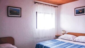 A bedroom with two beds, a window with white curtains, and a nightstand with a lamp. - Stunning home in Kornati with house sea view (Kornati)