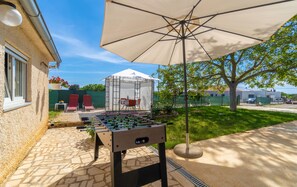 Relax in the outdoor recreational area, featuring a foosball table, shaded seating, and a covered patio.