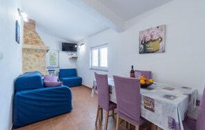 Cozy living space with a dining area, featuring a sofa, dining table, chairs, and a mounted television.