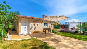 A house with a tiled roof, a front door, and a patio area with a table and chairs. - 1 bedroom amazing apartment in Pula (Pula)
