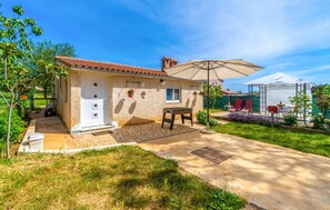 A house with a tiled roof, a front door, and a patio area with a table and chairs. - 1 bedroom amazing apartment in Pula (Pula)