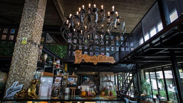 A restaurant interior with a chandelier, a counter with food items, and a sign that reads "Kampung." - Quip Bed & Breakfast (Phuket)