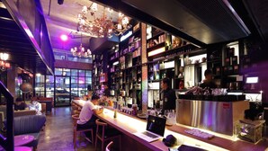 A modern bar area with a laptop on the counter, bar stools, and a bartender. - Quip Bed & Breakfast (Phuket)