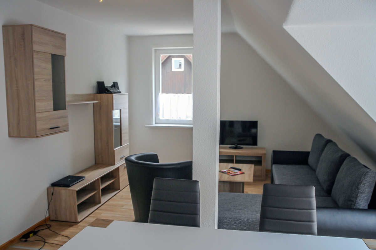 Un espacio habitable moderno con televisor, sofá y mueble de entretenimiento de madera.